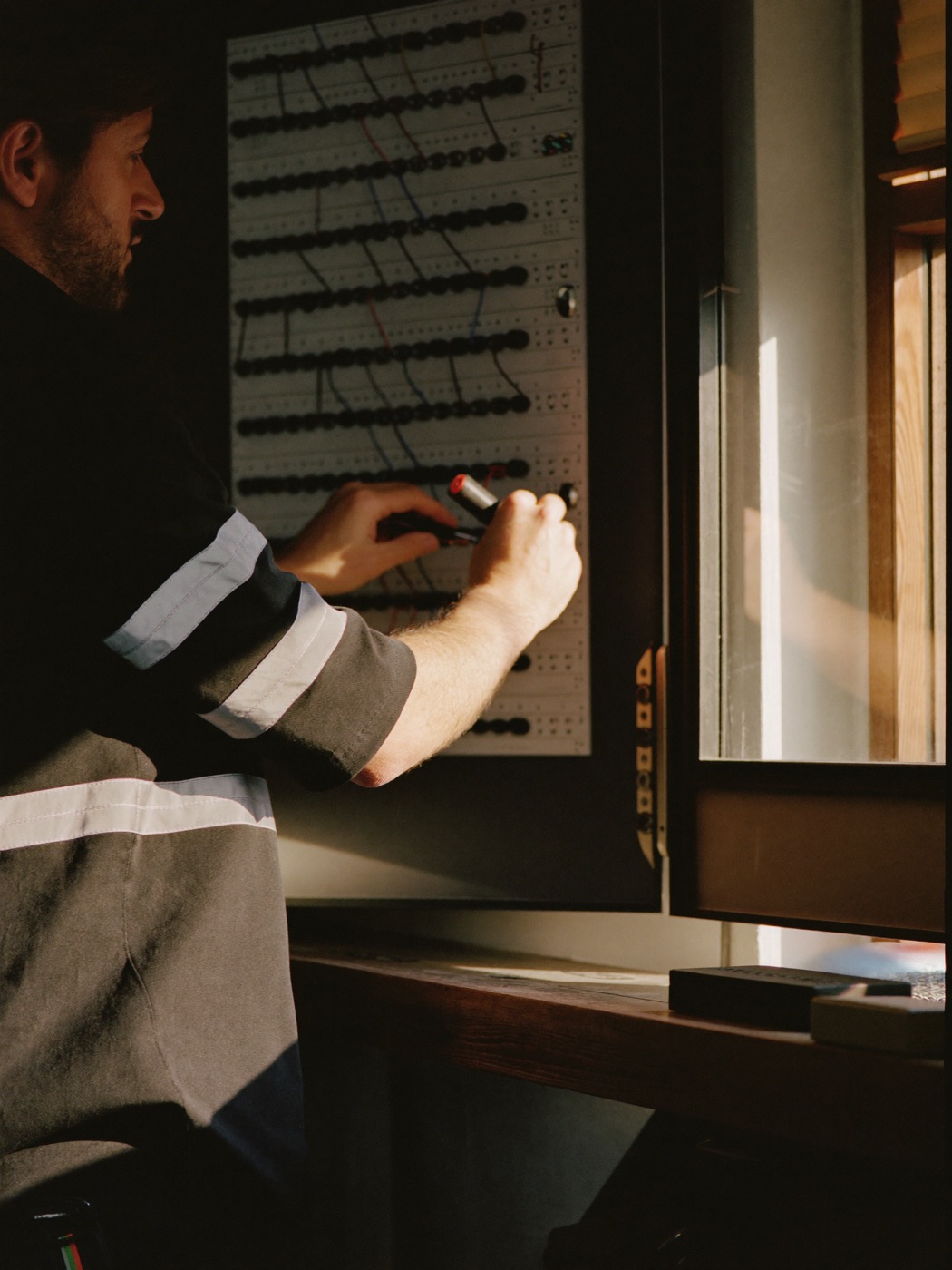 Elektriker bei der Arbeit an einem offenen Schaltschrank, natürliches Licht